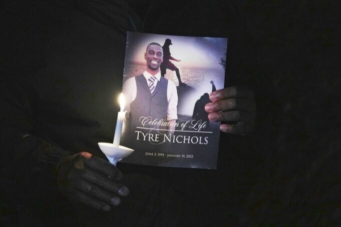 Seorang pria memegang lilin dan foto nichols ban.