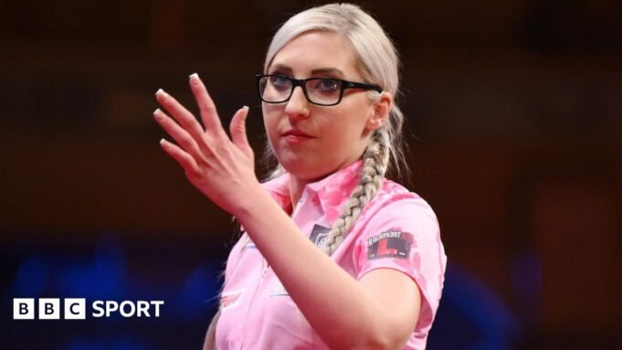 Fallon Sherrock waves her hand during a darts match