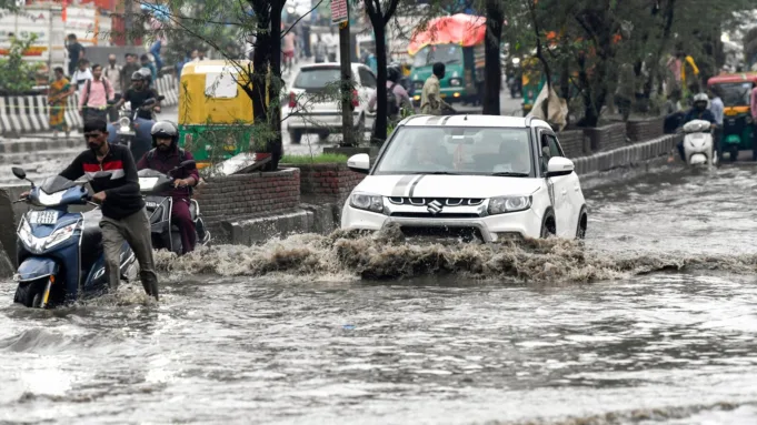 Commuters wade through a waterlogged road after heavy rainfall, in New Delhi on Wednesday.