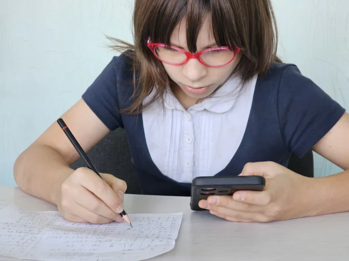 child using smartphone while doing homework