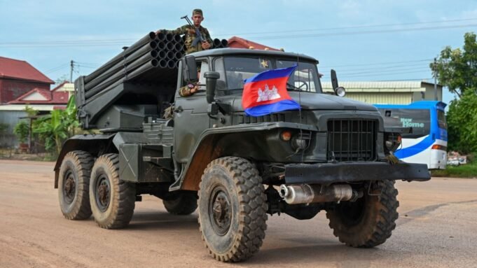 A Cambodian soldier stands on a truck carrying a Russian-made BM-21 rocket launcher travelling along a street in Oddar Meanchey province on July 25, 2025. 