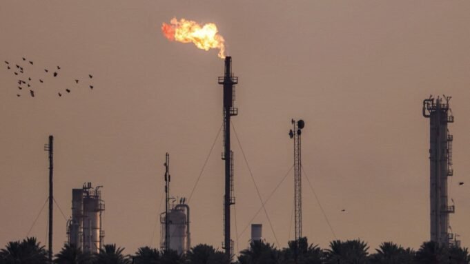A flock of birds flies past burning gas flares at the Dora (Daura) Oil Refinery Complex in Baghdad on July 15, 2025.
