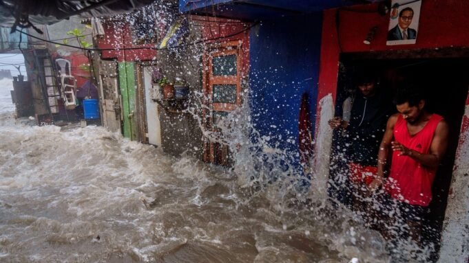 Men watch as waves hit houses during high tide on the shore of the Arabian Sea in Mumbai, India, Wednesday, June 25, 2025. (AP Photo/Rafiq Maqbool)