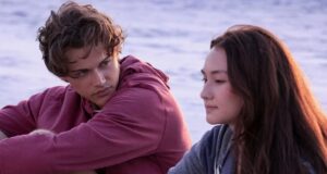 Conrad looks longingly at Belly while sat on the beach