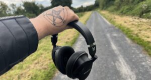 A woman holding the Heavys headphones outside