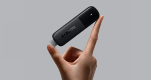 A hand holding a Xiaomi TV Stick 4K (2nd gen) in front of a grey background