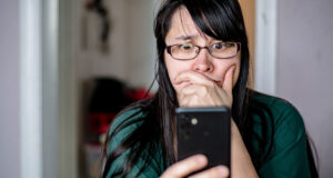 A woman looking at her phone with a concerned expression