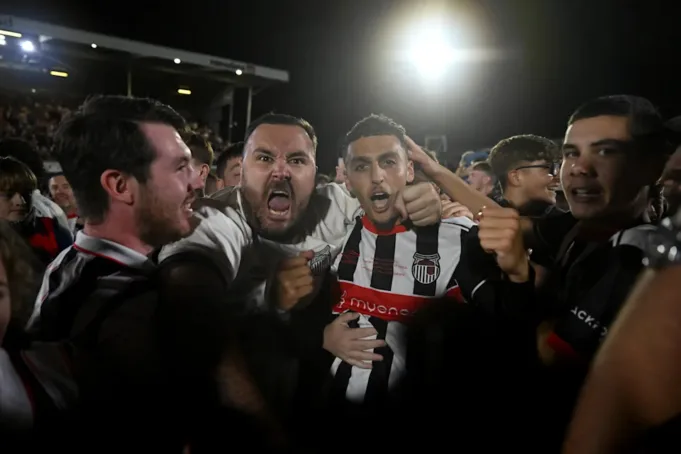 Pendukung Grimsby Town merayakan dengan pemain setelah menyerbu lapangan. (Shaun Botterill/Getty Images)
