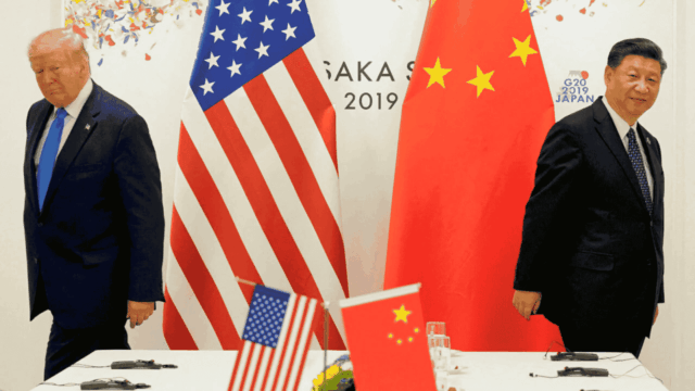 Mantan Presiden Donald Trump berpidato di podium dengan ekspresi tegas, bendera AS dan Tiongkok dipajang berdampingan di latar belakang. Simbol-simbol ekonomi seperti grafik tarif, kontainer kargo, dan panah bawah yang bersilangan menggambarkan meningkatnya ketegangan perdagangan yang dijelaskan dalam pidatonya.